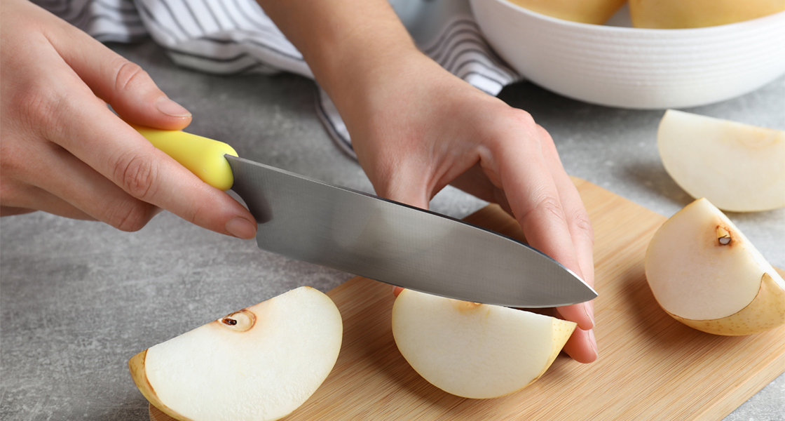 Person slicing an Asian pear with a knife