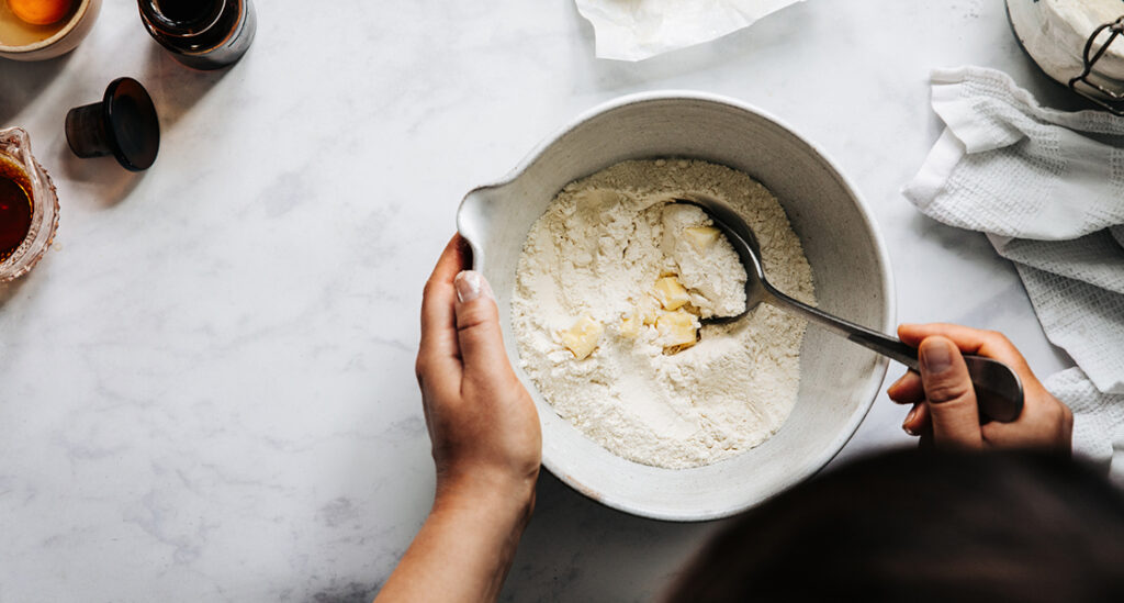 Person preparing dough with flour and butter