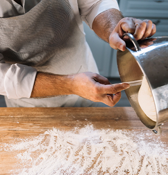 A baker placing dough onto a floured counter